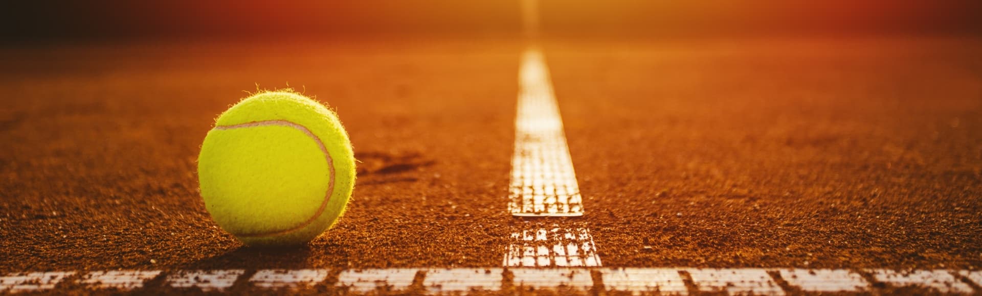 Gelber Tennisball an der Seitenlinie auf einem Tennisplatz mit roter Asche